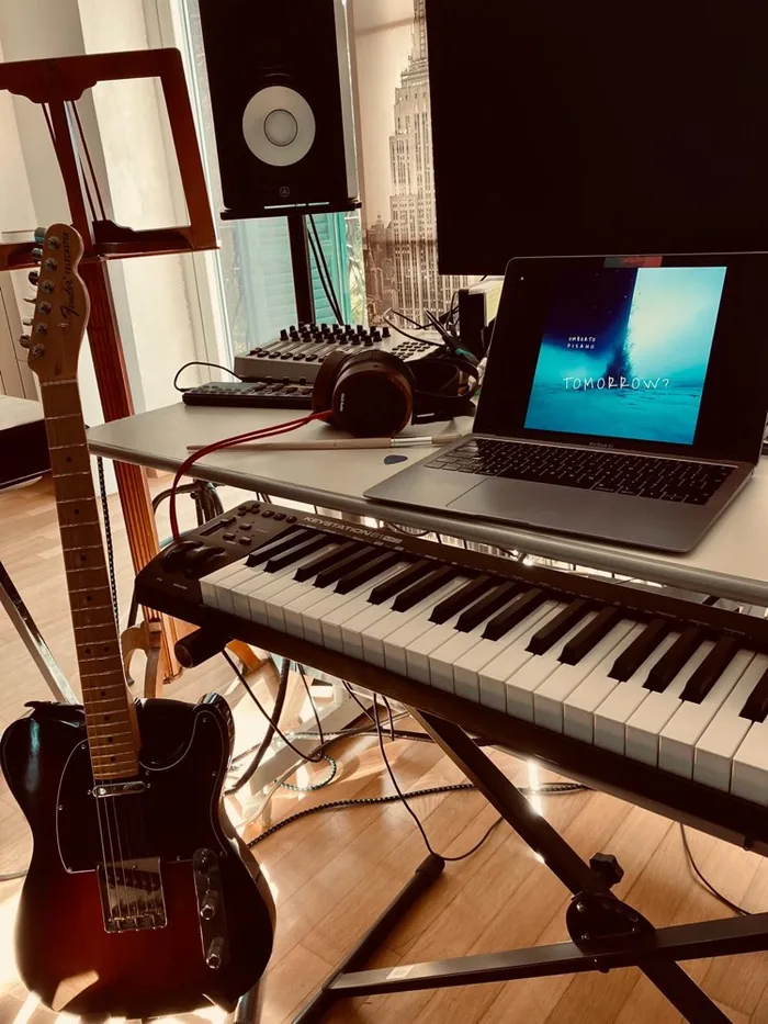 A Telecaster, MIDI keyboard and laptop showing the artwork for Tomorrow?, lit by afternoon sun